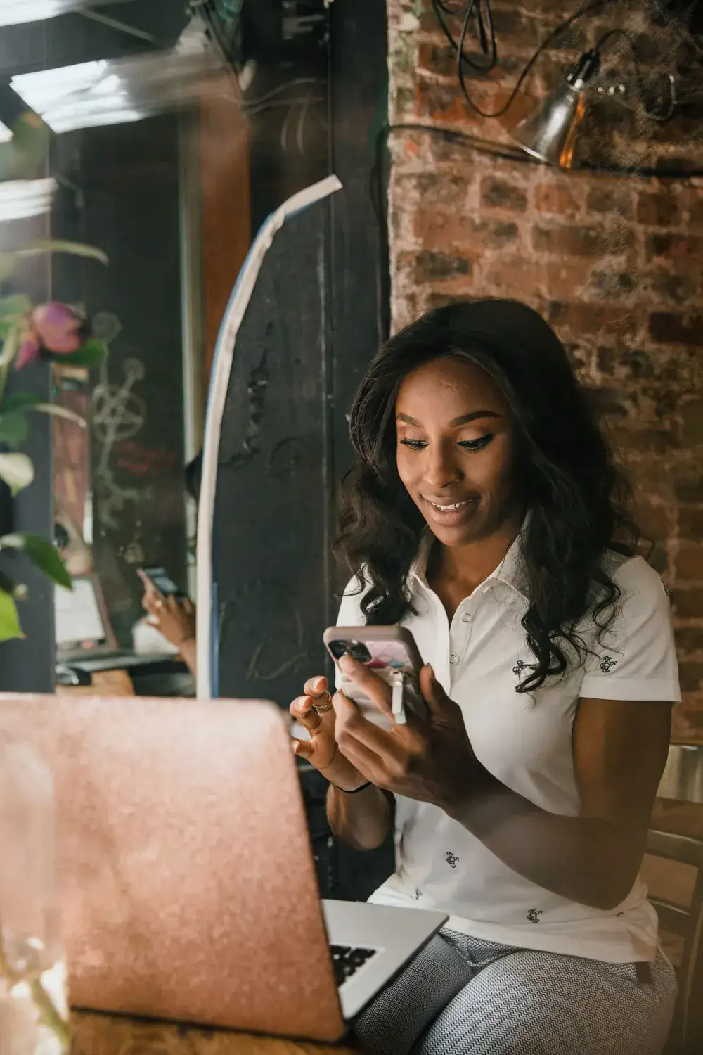 Small-business operator using a smartphone and laptop to manage local customer activity.