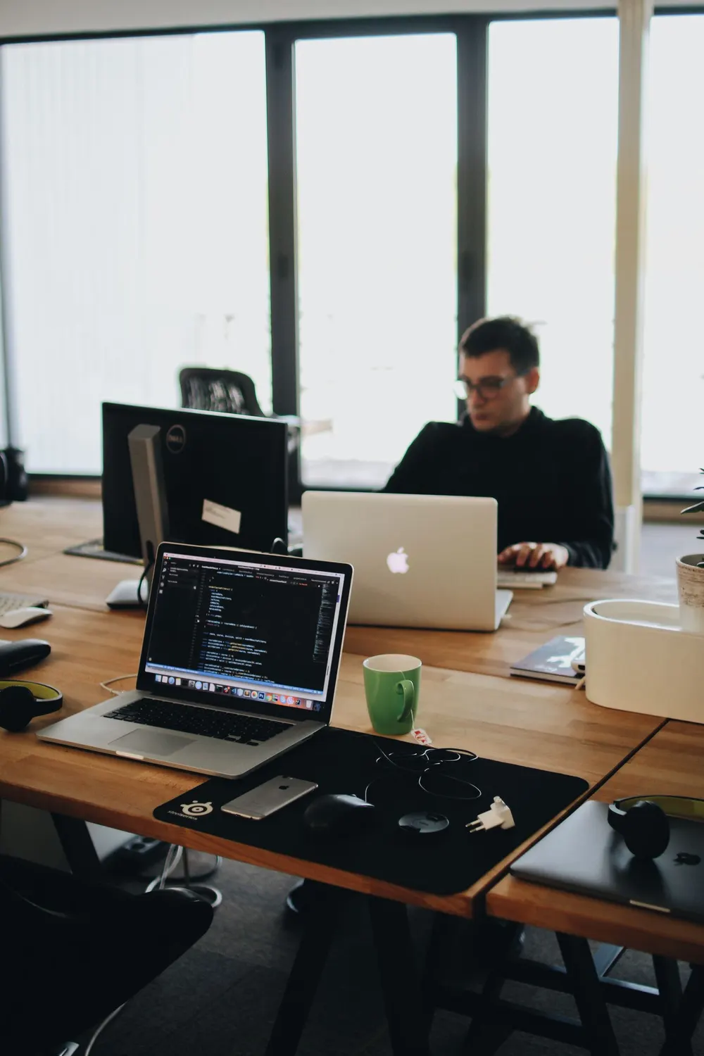 Developer working at a multi-screen desk while coding a custom small-business website.